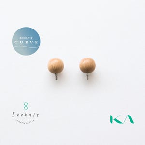 May include: Two wooden knitting needle stoppers with a round, light brown ball design. The stoppers have a silver-coloured metal pin. The image also includes the text "SEEKNIT CURVE" in a blue circle and the Seeknit logo.
