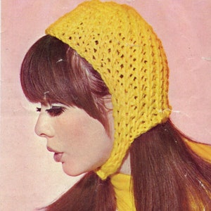 May include: A woman with long brown hair is wearing a yellow crocheted hat with a long flap that hangs down her back. The hat has a lacy pattern.