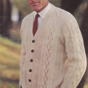 May include: A cream-colored cable knit cardigan with brown buttons and a red tie. The cardigan has a V-neck and long sleeves.