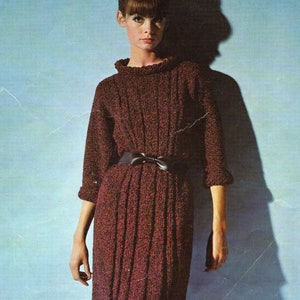 May include: A maroon knitted dress with a black belt. The dress has a high neck and a fitted silhouette. Six sizes: 34-44 inch bust, 36-46 inch hips.