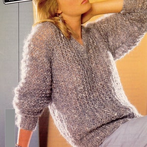 May include: A light grey knitted jumper with a V-neck and long sleeves. The jumper is made of a soft, fuzzy yarn. The model is wearing the jumper with a pair of light blue trousers. The text "76-97 cm 30-38 in Teens sizes included" is visible in the top right corner of the image.