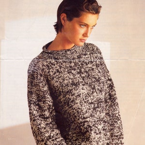 May include: A black and white speckled sweater with a round neckline and long sleeves.