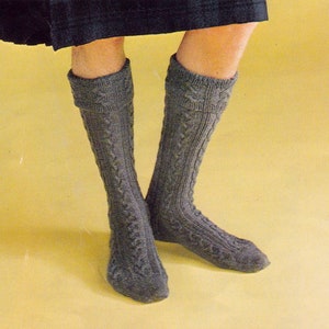 Puede incluir: Un par de calcetines grises de punto de cable hasta la rodilla.