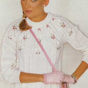 May include: White cable knit sweater with a floral design and pink accents. The sweater is 32-38 inches and is made of double knit fabric.