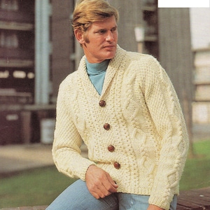May include: Cream-coloured, button-down cardigan sweater with a shawl collar. The sweater features a cable knit design and is worn over a teal turtleneck. The text in the image reads: 38 - 44 inch chest (96.5 - 111.8 cm).