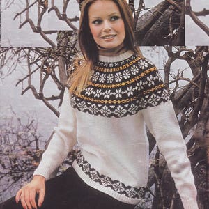 Peut inclure: Un pull en tricot blanc avec un motif géométrique brun, blanc et jaune autour du cou et de la taille. Le pull est porté par une personne aux longs cheveux bruns.