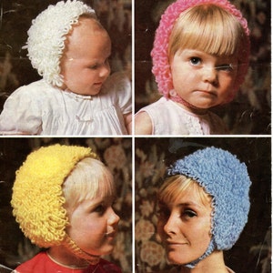 May include: Four knitted baby hats with ear flaps in white, pink, yellow, and blue. The hats are made with a fluffy yarn and have a simple design.