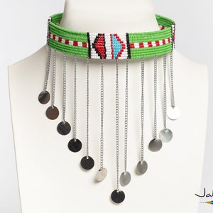 Peut inclure: Un collier ras de cou en perles vertes avec des accents rouges, blancs et bleus. Le collier a une frange de chaînes argentées avec des breloques rondes argentées.