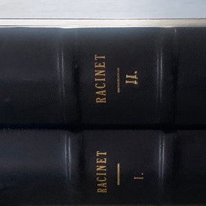 May include: Two black leather-bound books with gold lettering. The top book has the title "L'ORNEMENT - POLYCHROME RACINET II." The bottom book has the title "L'ORNEMENT - POLYCHROME RACINET I."