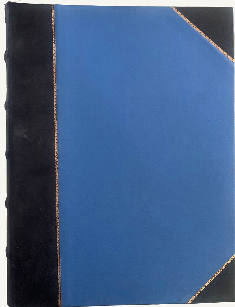 May include: A blue leather-bound book with a black spine and gold accents. The book is closed and the cover is smooth.