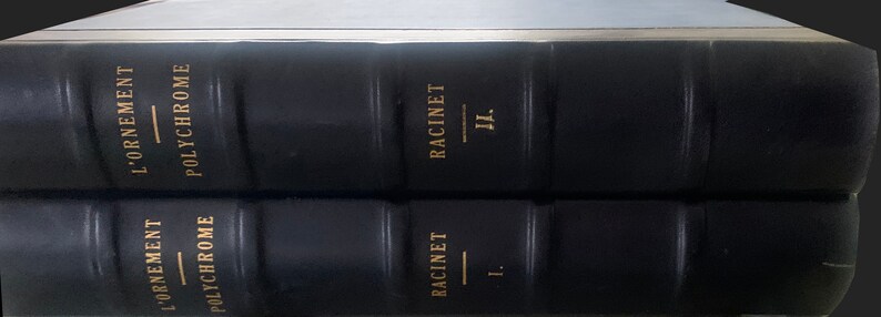 May include: Two black leather-bound books with gold lettering. The top book has the title "L'ORNEMENT - POLYCHROME RACINET II." The bottom book has the title "L'ORNEMENT - POLYCHROME RACINET I."