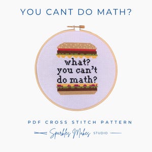 May include: A cross-stitch pattern in a wooden hoop features a burger design with the text "what? you can't do math?" in black. The text "YOU CANT DO MATH?" is above the hoop. The words "PDF CROSS STITCH PATTERN" and "Sparkles Makes Studio" are below.