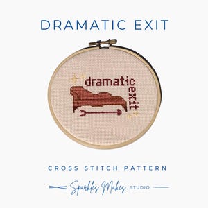 May include: A cross-stitch pattern in a wooden hoop with the words "DRAMATIC EXIT" above. The design features the word "dramatic" and "exit" with an arrow, all in brown thread. The text "CROSS STITCH PATTERN" and "Sparkles Makes Studio" are below.