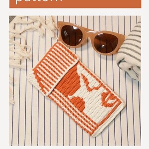 Könnte beinhalten: Eine gehäkelte Sonnenbrillenhülle mit einem weißen und orangefarbenen Streifenmuster. Die Hülle liegt auf einer gestreiften Stoffoberfläche. Der Text "Sunglasses pouch pattern" befindet sich oben im Bild.