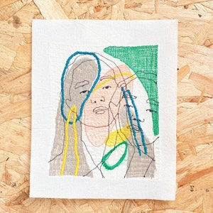 May include: Embroidered artwork featuring a stylized portrait of a person with a green, blue, yellow, and pink color scheme.