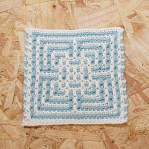 May include: A square crochet coaster with a geometric pattern in blue and white.