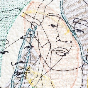 May include: A close-up of a textile art piece featuring a stylized embroidered face with multiple overlapping lines and a green, yellow, and pink color scheme.