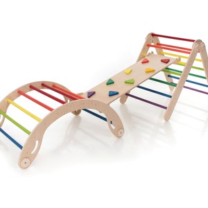 May include: A wooden climbing structure for children, featuring a rainbow-colored bridge, a ramp with colorful triangle shapes, and a climbing ladder.