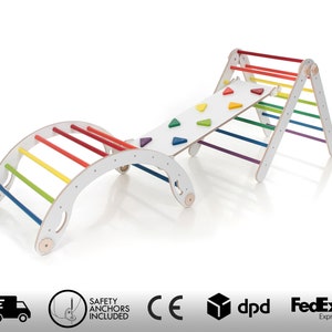 May include: A white wooden climbing frame with a rainbow ladder, a climbing wall, and a curved bridge. The frame is designed for children to climb and play on.