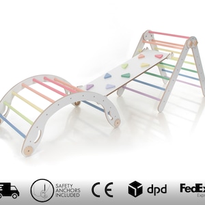 May include: A white wooden climbing frame with a rainbow-colored ladder and a slide. The frame has a curved archway and a flat platform with colorful climbing holds. The frame is designed for children to climb and play on.