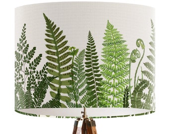 May include: A white lampshade with a green fern pattern. The lampshade is on a wooden tripod stand.