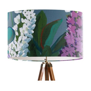 May include: A blue and green floral lampshade with white and purple flowers. The lampshade is on a tripod stand.