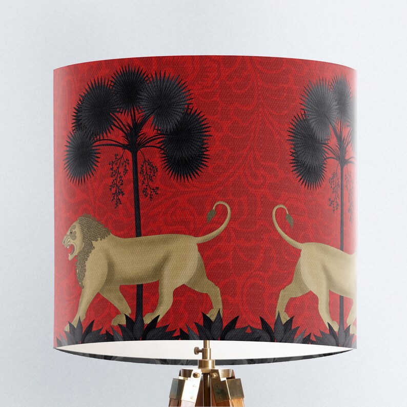 May include: Red lampshade featuring a black and gold lion design. The lions are walking through a jungle scene with palm trees and foliage.