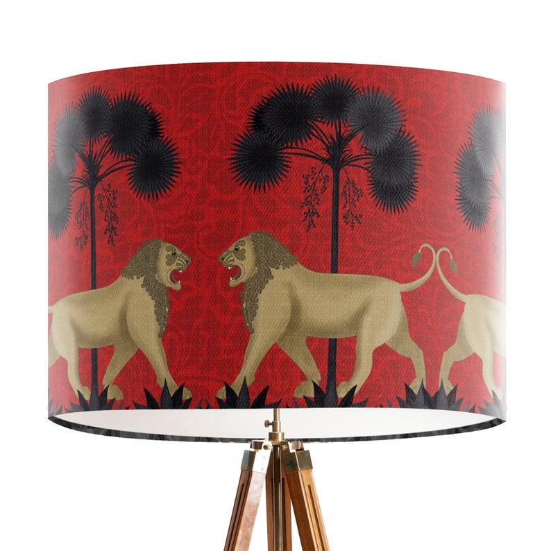 May include: A red lampshade featuring a design of black palm trees and gold lions facing each other. The lampshade is on a wooden tripod stand.