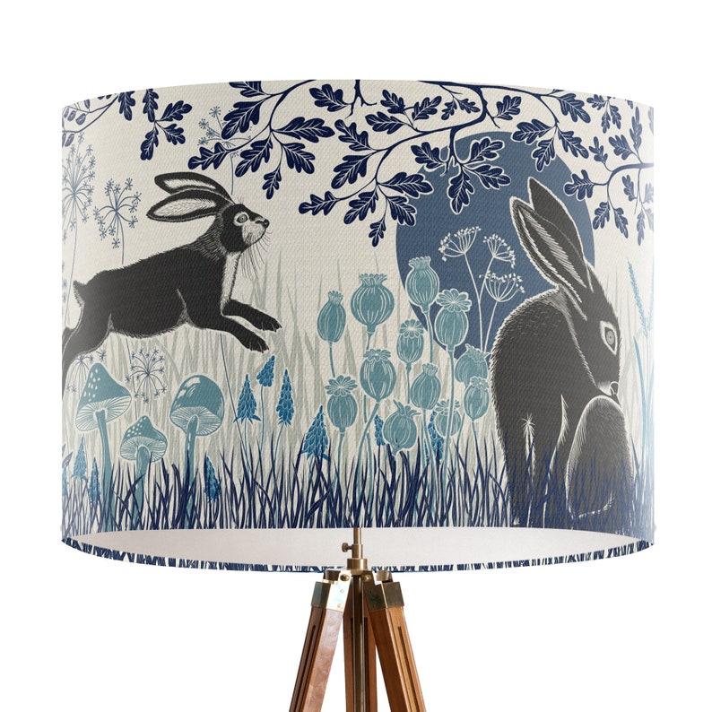May include: A lampshade with a blue and white woodland design featuring two hares, one running and one sitting, surrounded by flowers and mushrooms.