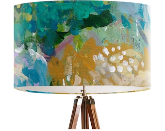 May include: A floor lamp with a tripod base and a drum lampshade featuring an abstract pattern of blue, green, yellow, and white paint.