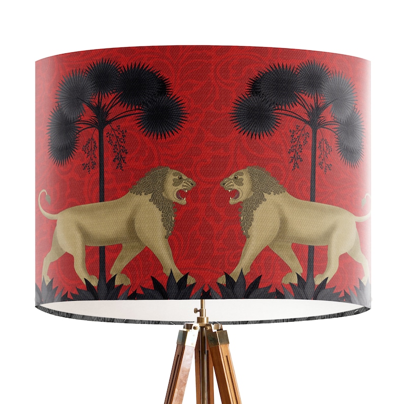 May include: A red lampshade with a black and gold design featuring two lions facing each other. The lions are surrounded by black palm trees and a red floral pattern.