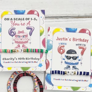 May include: Two birthday cards with balloon designs and the text "ON A SCALE OF 1-5, You're A 6 7" and "Justin's Birthday I WAS 6 NOW I'M 7". Two bracelets with the numbers 6 and 7. One bracelet is red and black, and the other is colorful.