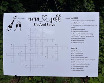 May include: A white sign with a crossword puzzle titled "Sip And Solve" for a wedding. The sign includes the names "ama jeff" and a list of clues, with illustrations of a champagne bottle and glasses.
