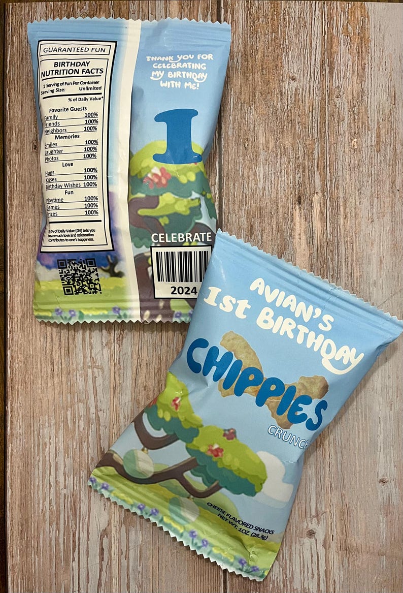 May include: A blue and white bag of cheese flavored snacks with the text "Avian's 1st Birthday Chippies Crunch" and a cartoon tree on the front. The back of the bag has a nutrition facts label with the text "Guaranteed Fun Birthday Nutrition Facts".