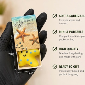 May include: A small yellow starfish-shaped stress toy with blue spots inside a cardboard box. The box lid features a beach scene with two starfish and the text 'You make a difference'. Dimensions are 2.0 inches by 1.4 inches as indicated on the image.