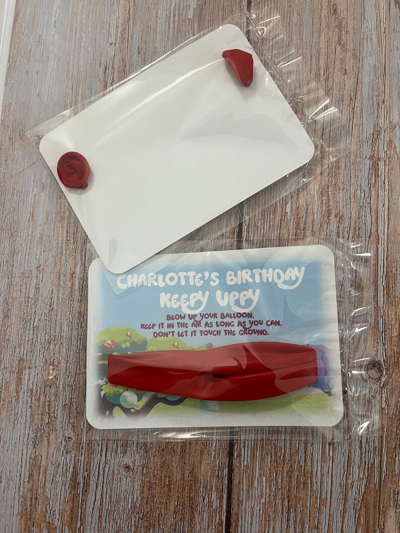 May include: A red balloon with the text "CHARLOTTE'S BIRTHDAY KEEPY UPPY" and instructions to blow up the balloon, keep it in the air as long as you can, and don't let it touch the ground.