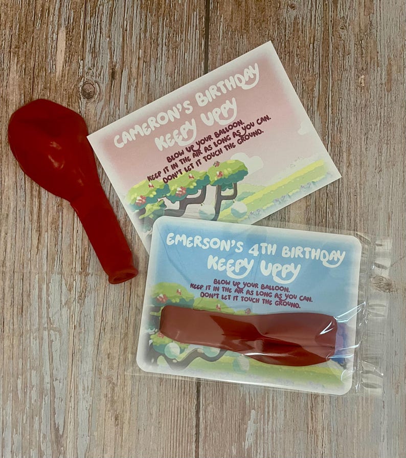 May include: Two birthday party game cards with red balloons. The cards are blue and pink with a cartoon tree and grass. The text on the cards reads 'Cameron's Birthday Keepy Uppy Blow Up Your Balloon. Keep It In The Air As Long As You Can. Don't Let It Touch The Ground.' and 'Emerson's 4th Birthday Keepy Uppy Blow Up Your Balloon. Keep It In The Air As Long As You Can. Don't Let It Touch The Ground.'
