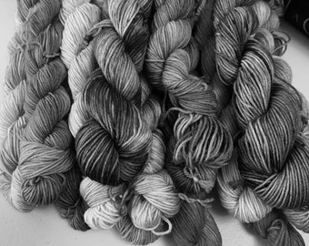 May include: A pile of black and white yarn skeins, with a gradient of color from dark to light.