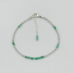 May include: Delicate bracelet featuring small, faceted emerald green beads interspersed with tiny silver beads. The bracelet has a silver clasp and an adjustable chain. The design is simple and elegant, suitable for everyday wear or special occasions.