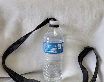 May include: A black adjustable strap with a clear plastic water bottle attached. The bottle has a blue label with text and a barcode.