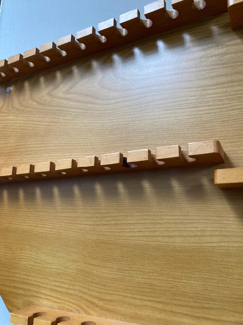 May include: A wooden wall-mounted organizer with multiple slots for storing items. The organizer has a light brown wood finish and is made of solid wood.
