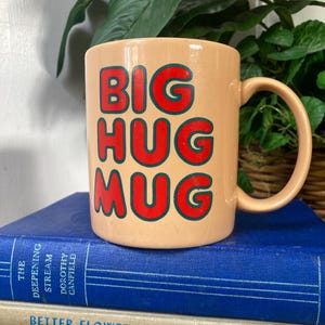 May include: A set of three ceramic mugs with a speckled, matte finish. The mugs are in shades of cream, light gray, and dark gray. Each mug has a simple, minimalist design and a rounded handle.