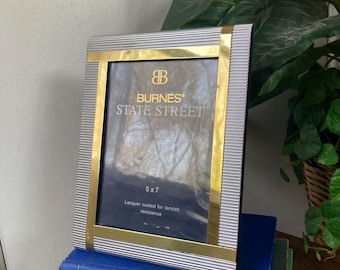May include: A rectangular photo frame with a silver and gold border, resting on a stack of books. The frame has the text "BURNES STATE STREET" and is sized 5x7 inches. The frame is lacquer coated for tarnish resistance.