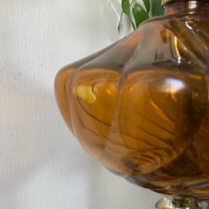May include: A vintage amber glass table lamp with a swirl design and a gold metal base.