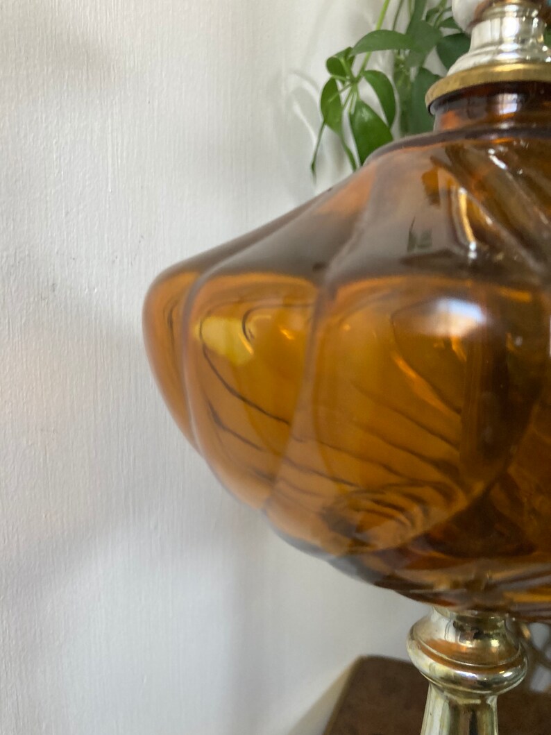 May include: A vintage amber glass table lamp with a swirl design and a gold metal base.