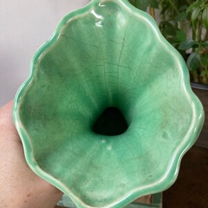 May include: A green ceramic vase with a wide, flared opening and a crackled glaze. The vase has a unique, organic shape.
