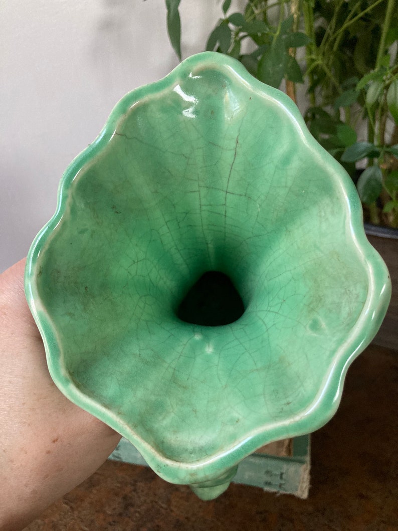 May include: A green ceramic vase with a wide, flared opening and a crackled glaze. The vase has a unique, organic shape.