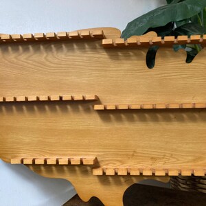 May include: Wooden wall shelf shaped like the United States of America with three rows of slots for displaying items.