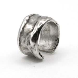 May include: A silver ear cuff with a textured, hammered finish. The cuff is open and has a slightly curved shape.