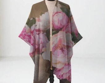 May include: A sheer brown floral kimono with a pink and white peony print. The kimono is draped over a black stand.